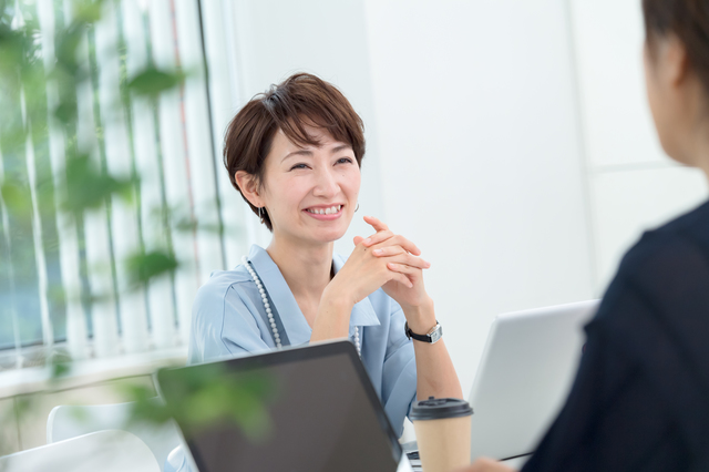 会議で同僚と話す女性